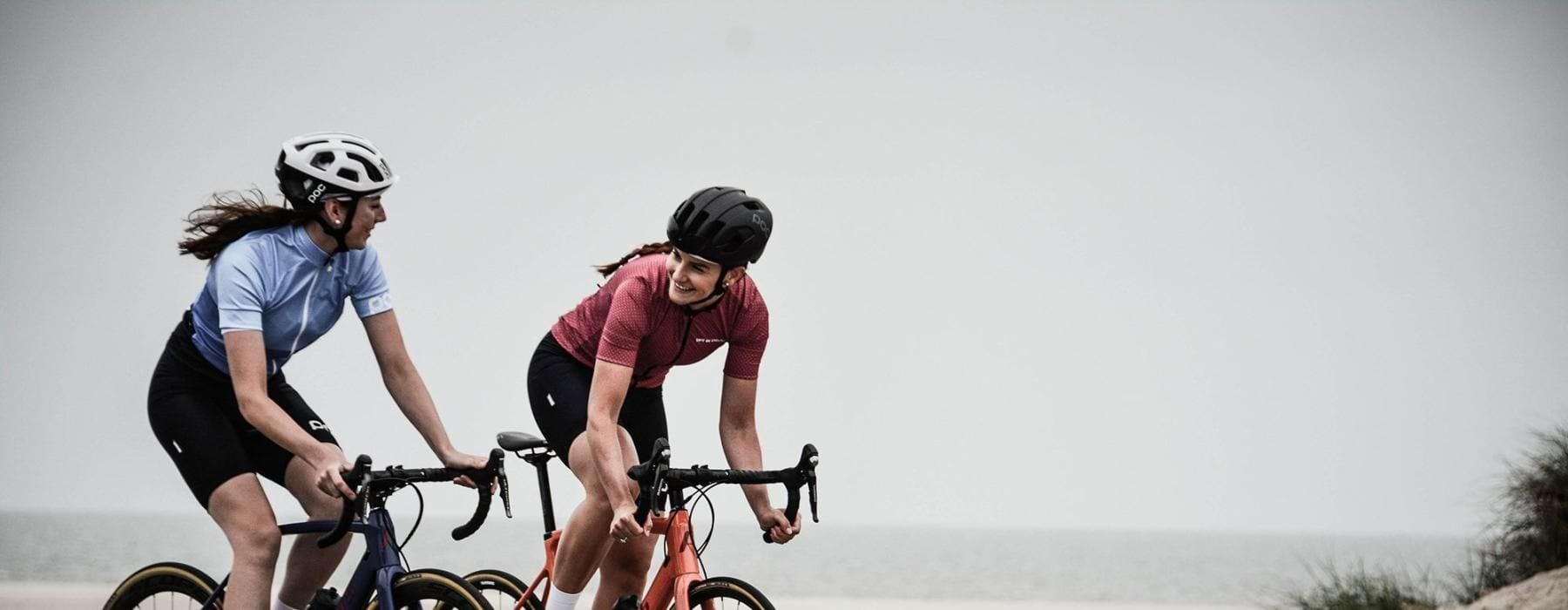 women bicycling on the road along a beach